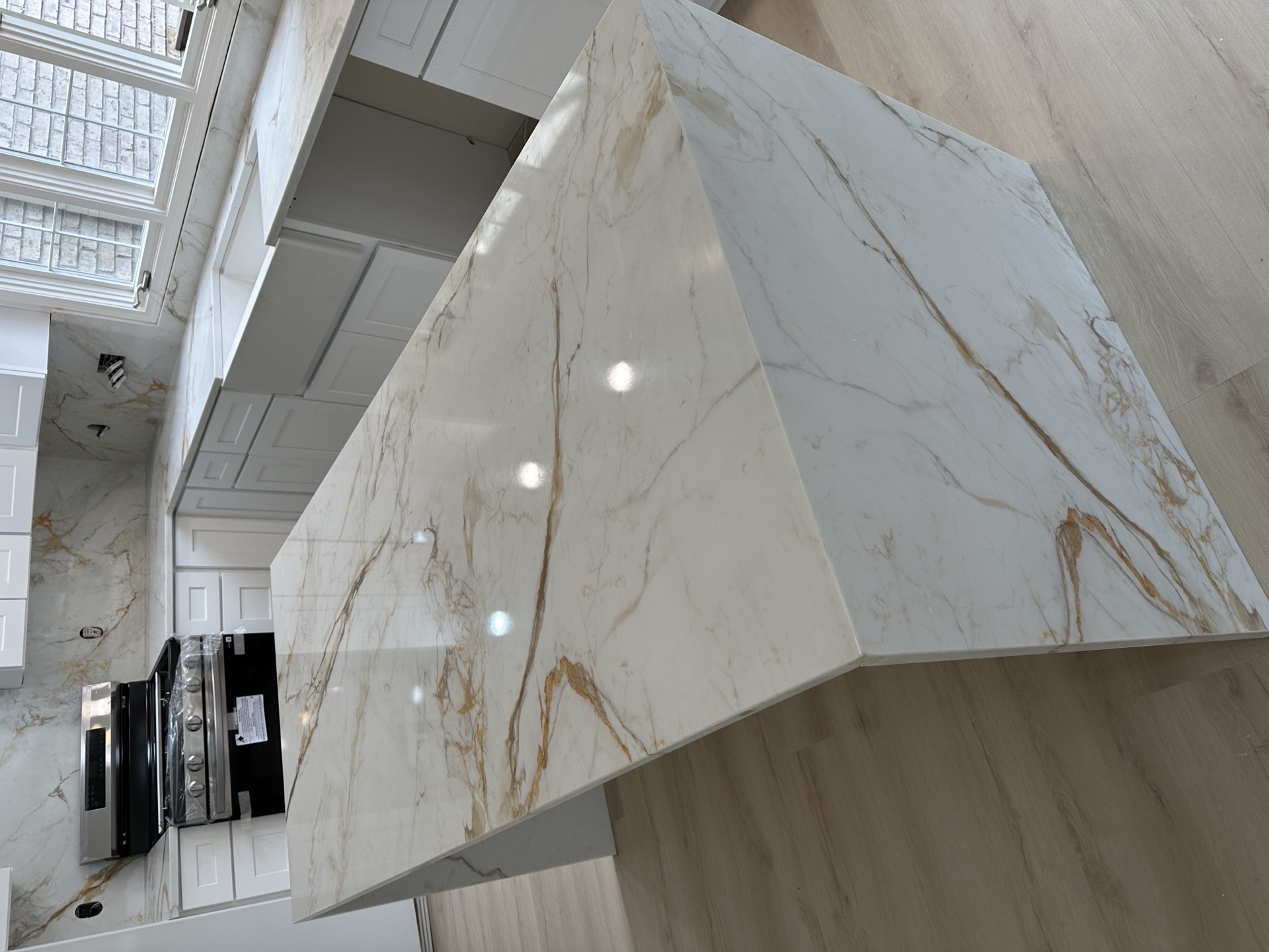 Waterfall-edge stone kitchen island with gold and grey veining, fabricated and installed by Stoneworx